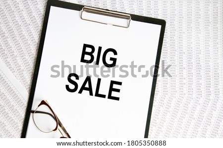 On a sheet of paper, the inscription BIG SALE is written to the letter tablet, next to the report.
