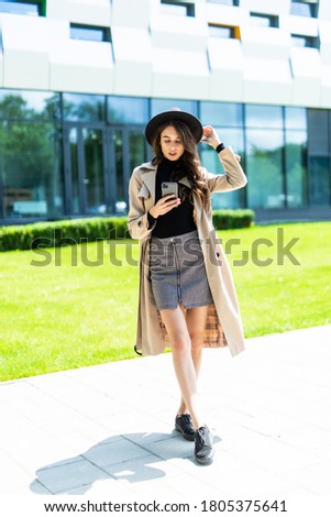 Happy woman walking and using a smart phone on the street