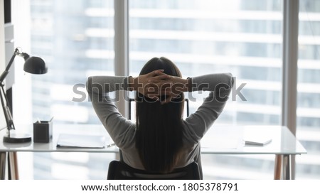 Rear view young businesswoman leaning back in comfortable chair, sitting in modern office, successful woman employee looking out window, planning future, visualizing, pondering project strategy Royalty-Free Stock Photo #1805378791