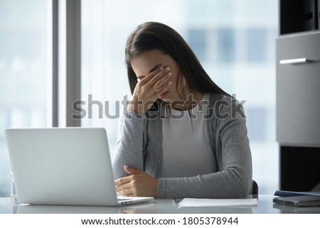 Exhausted tired young businesswoman massaging eyelids, feeling eyestrain, sitting at table in office, woman employee student suffering from dry eye syndrome, fatigue after long laptop use Royalty-Free Stock Photo #1805378944