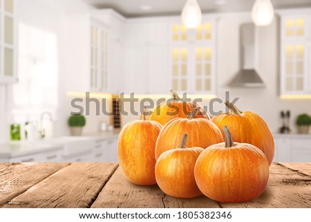 Fresh pumpkins on wooden table in kitchen. Space for text