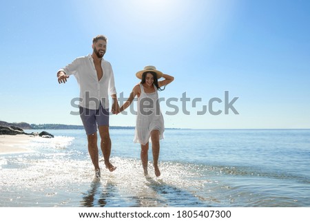 Happy young couple running on beach near sea. Honeymoon trip Royalty-Free Stock Photo #1805407300