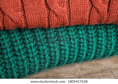 Folded warm sweaters on wooden table, closeup