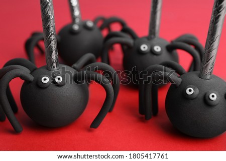 Delicious spider shaped cake pops on red background, closeup. Halloween treat