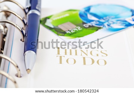 Credit card and the ball pen on the page of an organizer with the words "what to do"