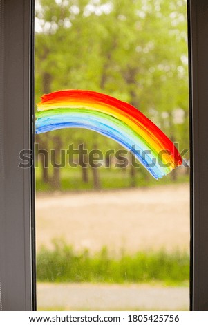 Close-up photo of painting rainbow on window. Rainbow painted with paints on glass.