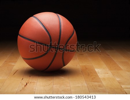 A basketball with a dark background on a hardwood gym floor