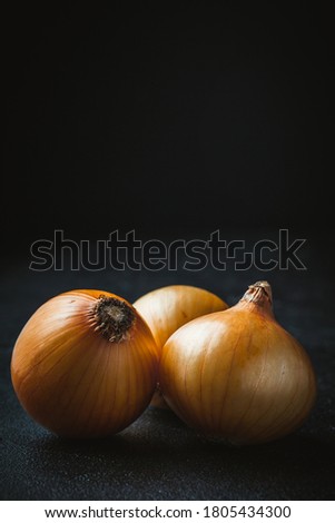 A set of white onion bulbs with golden shell. macro shot on the dark background
