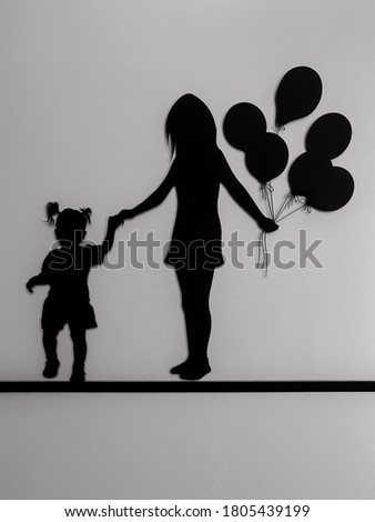 silhouette of a girl and her mother holding hands carrying some balloons with white background