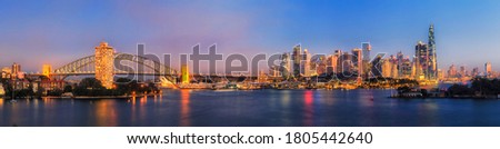 Dark panorama of Sydney city CBD skyline across harbour from Lower North Shore lookout.