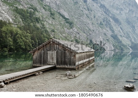 Wooden boathouse with jetty on beautiful Lake Obersee in Berchtesgadener Land on a sunny morning in summer. Mountain landscape with Alps in the background. Schoenau am Koenigssee, Bavaria, Germany. Royalty-Free Stock Photo #1805490676