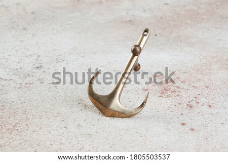 Brass anchor on concrete background. Home decor, copy space for text.