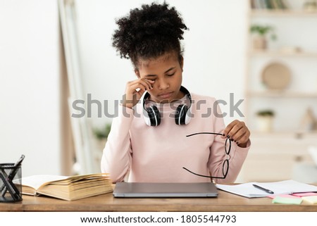 Eyesight Problem. Tired Black Teen Girl Touching Aching Eye Holding Eyeglasses Sitting At Laptop At Home Royalty-Free Stock Photo #1805544793