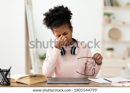 African Teen Girl Massaging Tired Eyes Having Poor Eyesight Sitting At Desk At Home, Holding Eyeglasses. Healthcare And Sight Problem Royalty-Free Stock Photo #1805544799