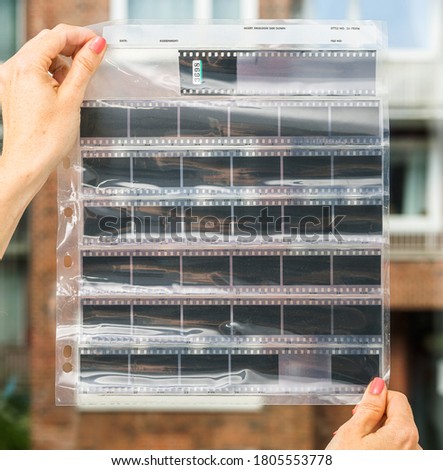 female hands holding blank or empty black and white 35mm film strips behind foil sleeve, cool photo placeholder, blend in your work via blend mode.