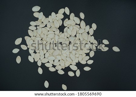 A pile of pumpkin seeds on a black background.
