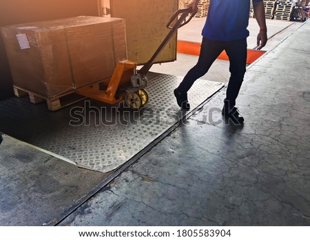 Worker driving forklift loading shipment carton boxes goods on wooden pallet at loading dock from container truck to warehouse cargo storage in freight logistics, transportation industrial, delivery Royalty-Free Stock Photo #1805583904