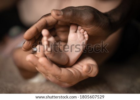 interracial family holding baby feet in hands mixed by black and white skin color Royalty-Free Stock Photo #1805607529