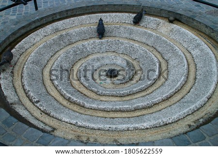 Spiral fountain on the ground that is used for drinking by pigeons. Council Square in Brasov, Romania.