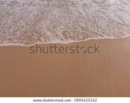 White sea waves on brown sand beach