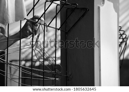 Black and white a woman's hand is taking a coat hanger on the iron fence