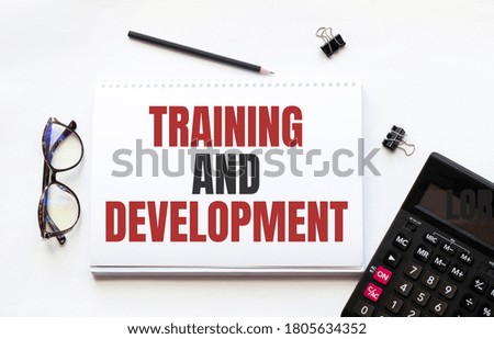 Business concept. Notebook with text TRAINING AND DEVELOPMENT sheet of white paper for notes, calculator, glasses, pencil, pen, in the white background