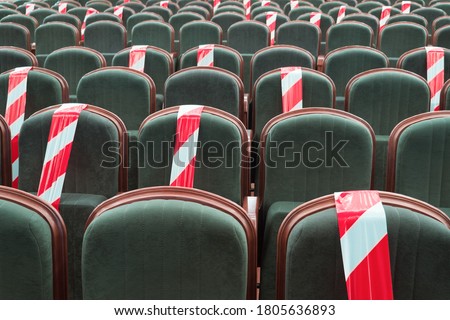 Social distancing during the crisis of Covid, coronavirus. Keeping your distance during a show, concert or play in a theater or cinema, conference hall. Empty rows of places marked with a warning tape Royalty-Free Stock Photo #1805636893