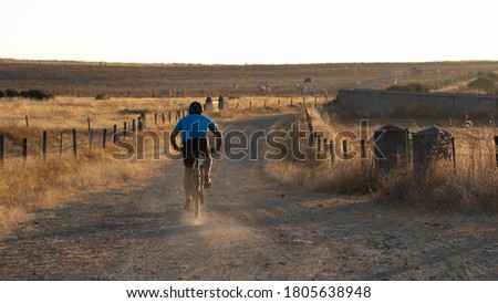 Mountain biker during a sunset on a dirt road. Personal improvement, cycling training and motivation