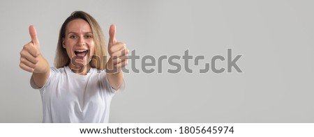Success smiling woman showing both thumbs up. Excited beautiful woman isolated on grey gray background. Caucasian model in studio, succes and luck concept, copy space, banner