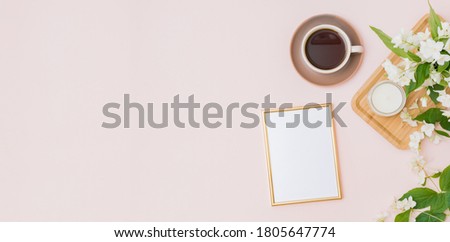 Mockup gold frame with a cup of coffee and jasmine flowers on a color background