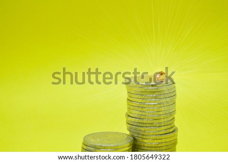 Coins stacked on a yellow background and ants atop, a great small power concept.