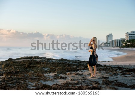 lovely blond female in bikini ready for beach at sunrise near rocky section of florida atlantic coast