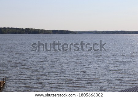 Calm flowing lake with a forest background and a pier in the foreground