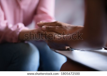 Close up African American psychotherapist holding clipboard, touching patient hands, expressing empathy and support at meeting, counselor therapist comforting girl during personal therapy session Royalty-Free Stock Photo #1805672500