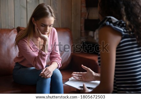 Unhappy depressed young woman listening to psychologist at meeting, African American woman therapist counselor consulting stressed frustrated girl at counselling therapy session, explaining diagnosis Royalty-Free Stock Photo #1805672503
