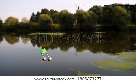 Fishing in the pond, fishing rod and iron double bell on the line in the foreground.                               