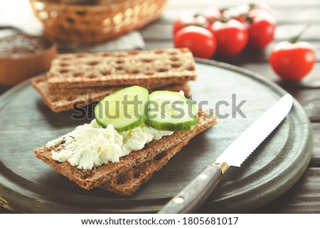 Crispbread with cream cheese and cucumbers on wooden board Royalty-Free Stock Photo #1805681017