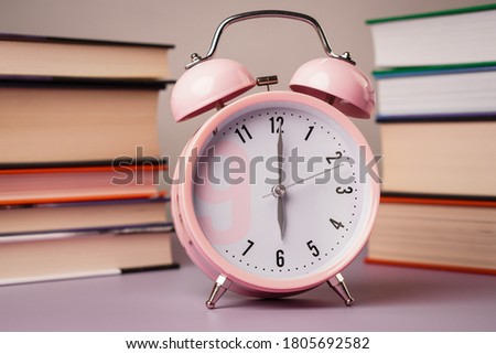 Time to school. Detail close up of the old pink vintage alarm. In the background are old books.