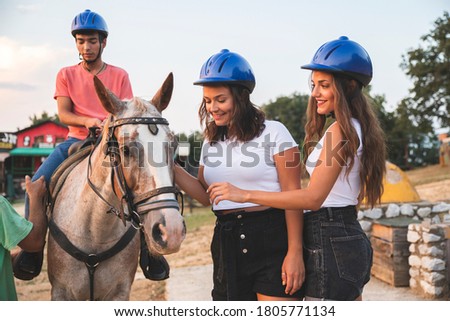 Two Girls Having Fun and Caressing a Horse and a Man Waits for His Ride. Ranch Concept Photography