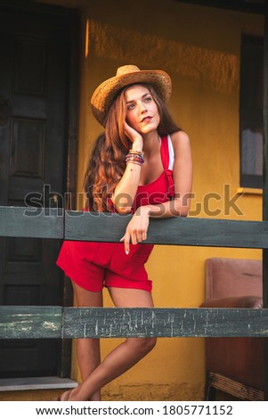 Beautiful Woman With a Cowboy Hat Posing in Front of a Yellow Wall Farm House. Fashion Concept Photography