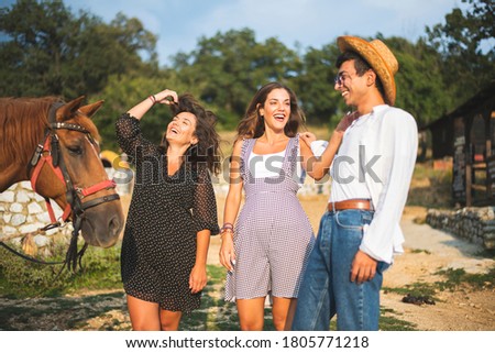 Three Friends Laughing and Having Fun in a Ranch with a Brown Horse. Ranch Concept Photography