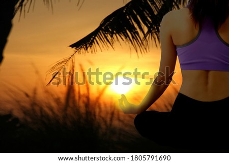 Asian woman  is meditating in lotus position with sun rise beauty sky