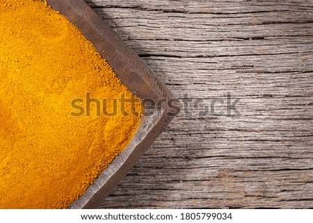 Turmeric powder in bowl on wooden background (Curcuma longa)
