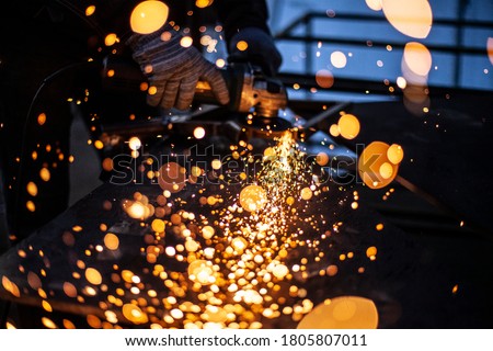 Metal processing in the workshop. Grinding metal. The worker makes the structure of a metal profile. Creating a shelving for the city dweller. Sparks from metal friction.