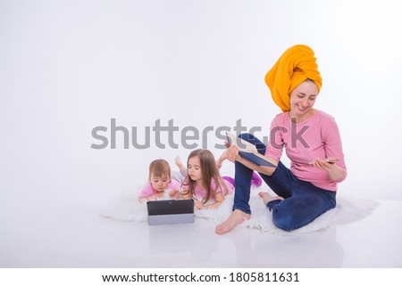 a woman with a book in her hands is talking on the phone. Children watch a cartoon on their tablet. mom washed her hair. towel on the head. Hobbies and recreation with gadgets. Family vacation, spend