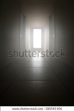 a long dark hallway with light coming from a big window