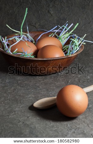 Raw eggs in wooden bowl on gray background . Close up
