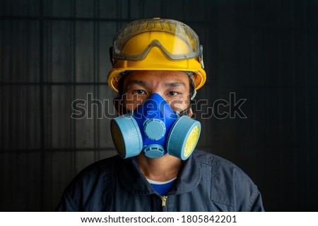 Asian worker wear wears a respirator in a smokey, toxic atmosphere. Image show the importance of protection readiness and safety in industrial factory. Royalty-Free Stock Photo #1805842201