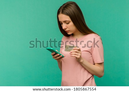 Photo of pleased happy screaming young woman posing isolated over blue wall background using mobile phone holding credit card. - image