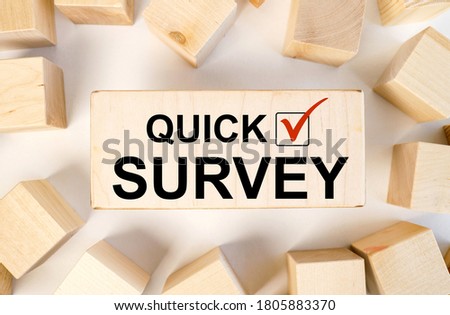 QUICK SURVEY. text on a wood block on a light background. there are a lot of wood cubes near the wooden block. view from above.